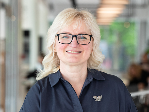 Naeratav naine prillidega kontoris töökaaslastega taustal