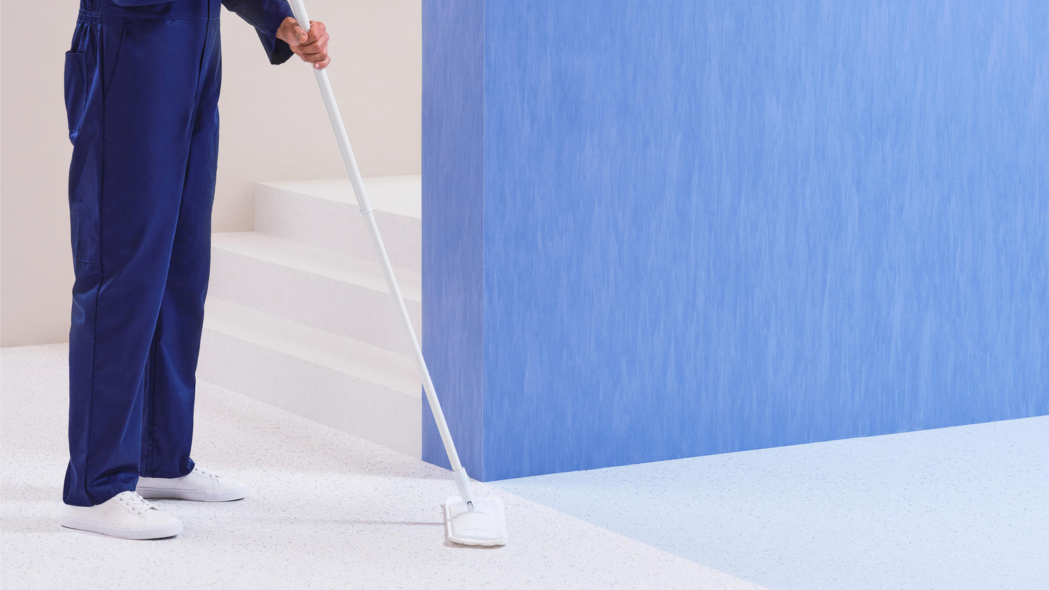 Inimene koristab põrandat sinise mopi ja varrega.