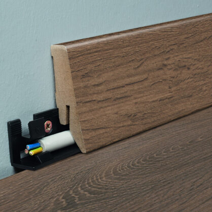 Kaabel koos puiduimitatsiooniga põrandaliistuga seinal