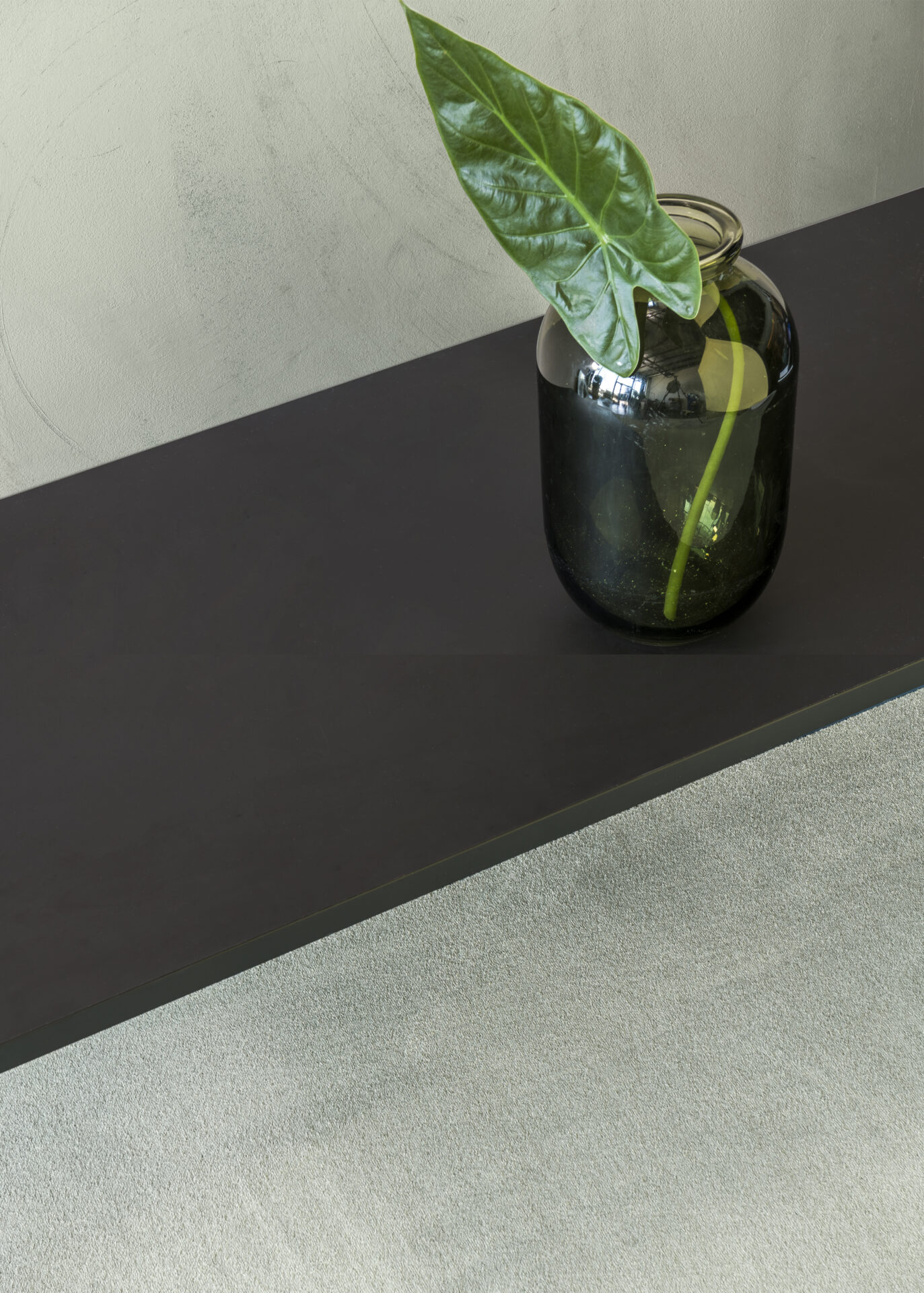 Roheline taim mustas klaaspudelis laual