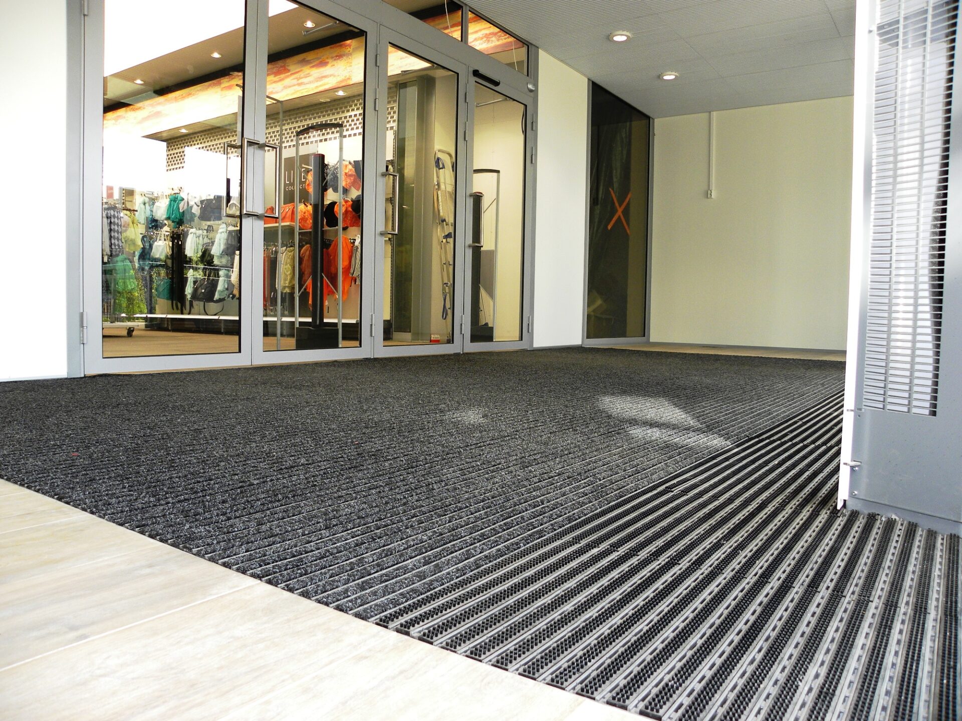 Poepood uksematt must ja hõbedane siseruumides.