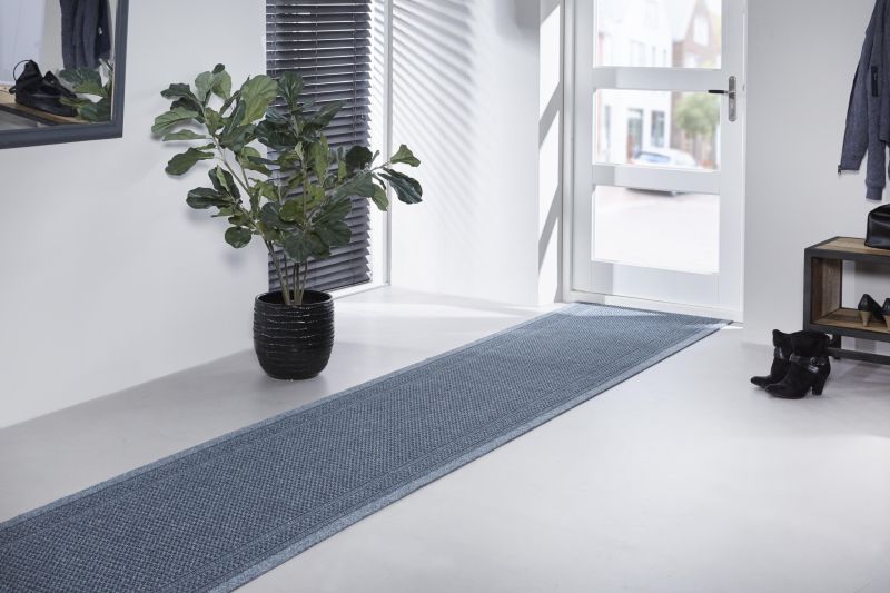 Sinine vaip heledal põrandal avaras koridoris.