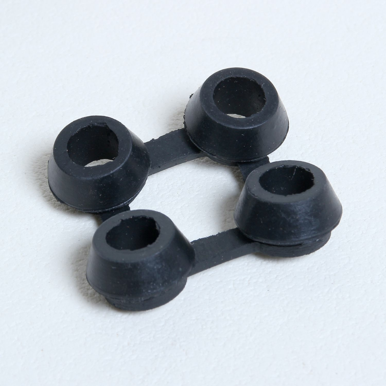 Neli musta kummist kaitsetihendit valgel pinnal