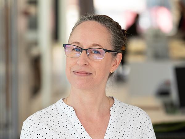 Naeratav naine kontorikeskkonnas prillidega töötamas.