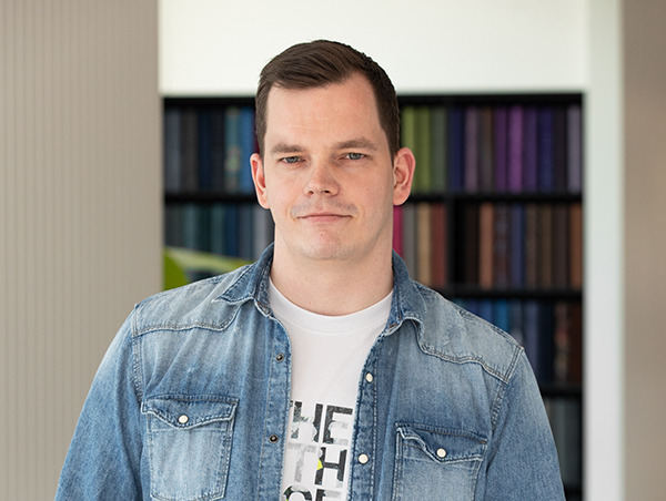 Mees teksariides raamatukogus taustal värvilised raamatud