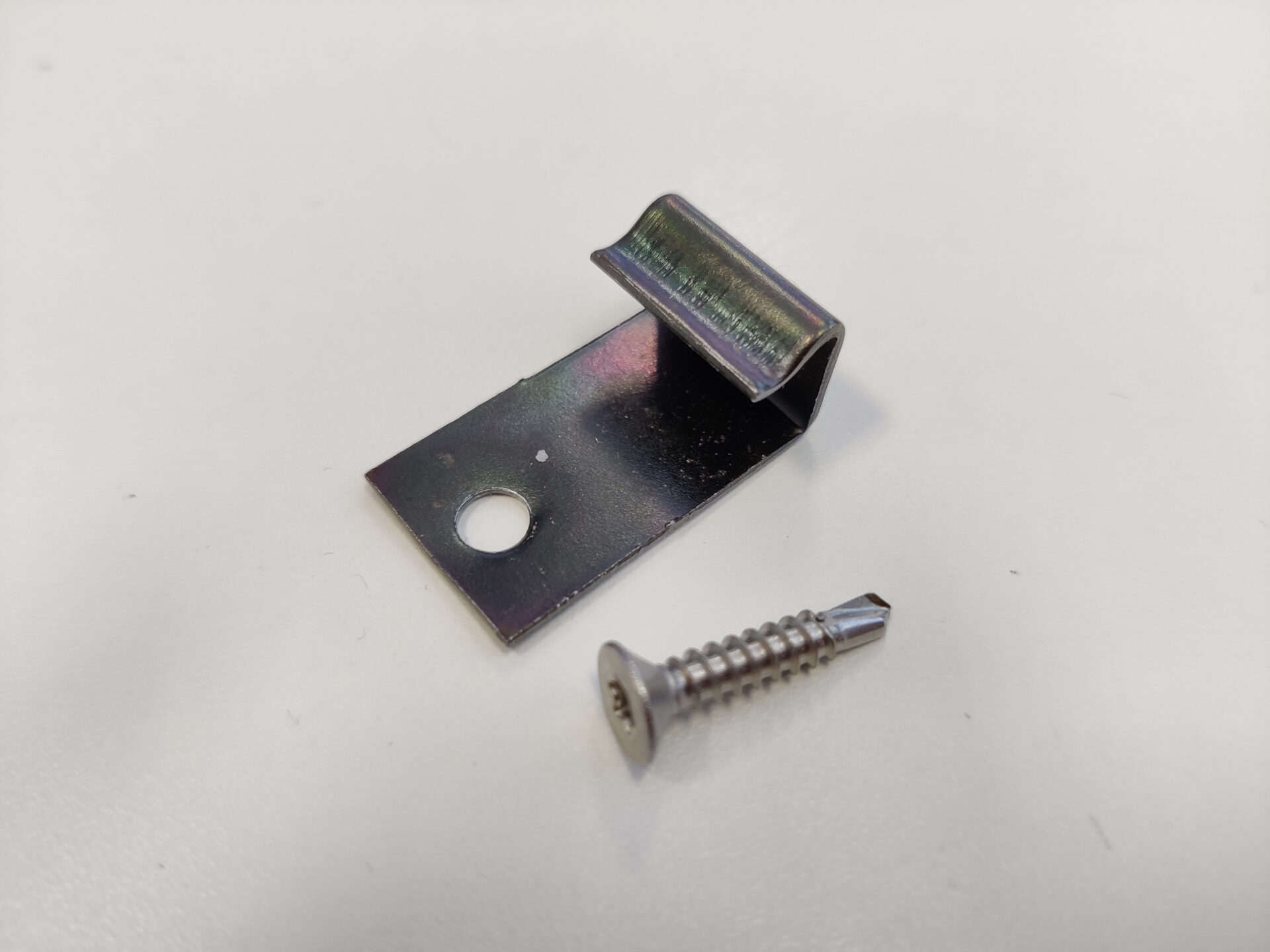 Metallklamber ja kruvi valgel taustal