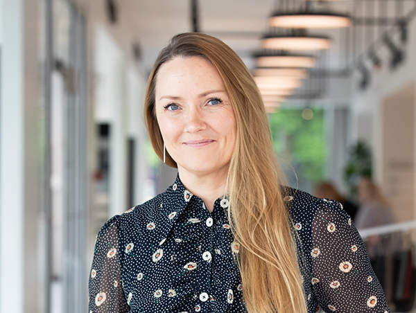 Naeratav naine musta mustriga pluusis kontori taustal